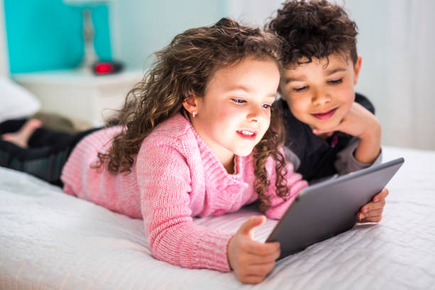 Two Cute brother and sister enjoying tablet at home